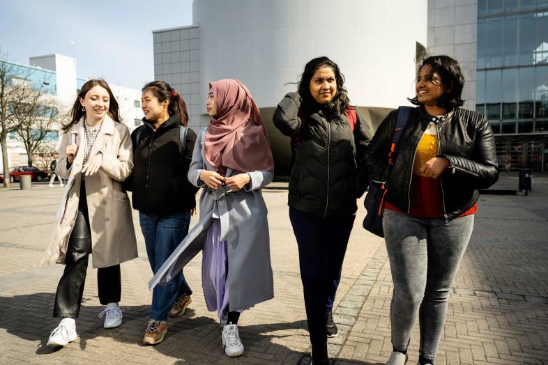 Five students walking in front of Chemicum at the Kumpula Campus.
