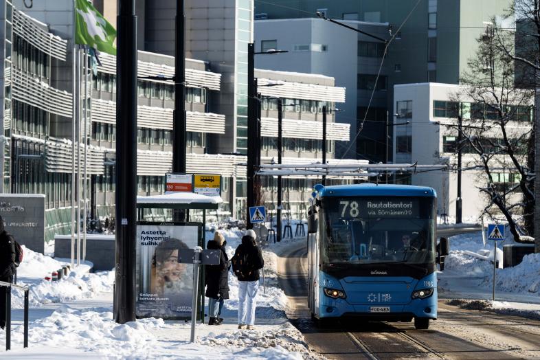 People getting on a bus in wintery Viikinkaari.