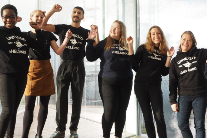 A group of joyful looking people posing in front of the window at Oodi library