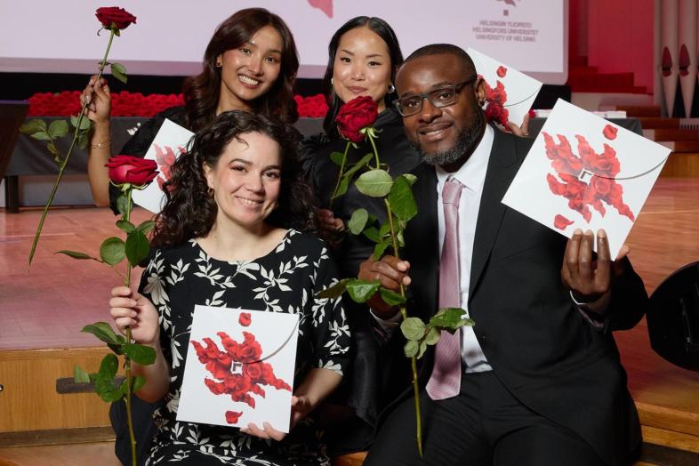 Fyra nybakade studenter med rosor och gratulationskort i händerna.