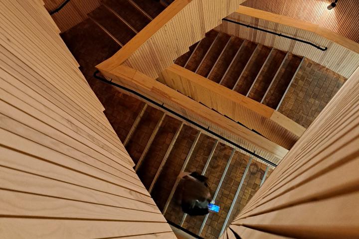 A student holding a cellphone, walking down the Think Corner stairs.
