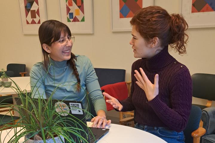 Kaksi opiskelijaa keskustelee kannettavan tietokoneen äärellä.