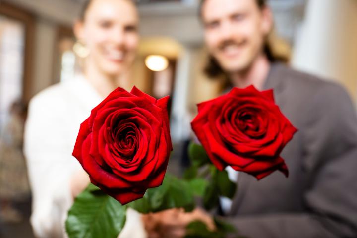 Kaksi henkilöä ruusut kädessä.